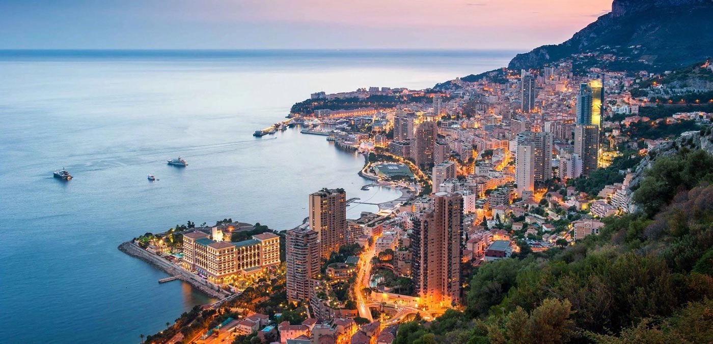 Monaco and the Mediterranean coastline seen from above at dusk.